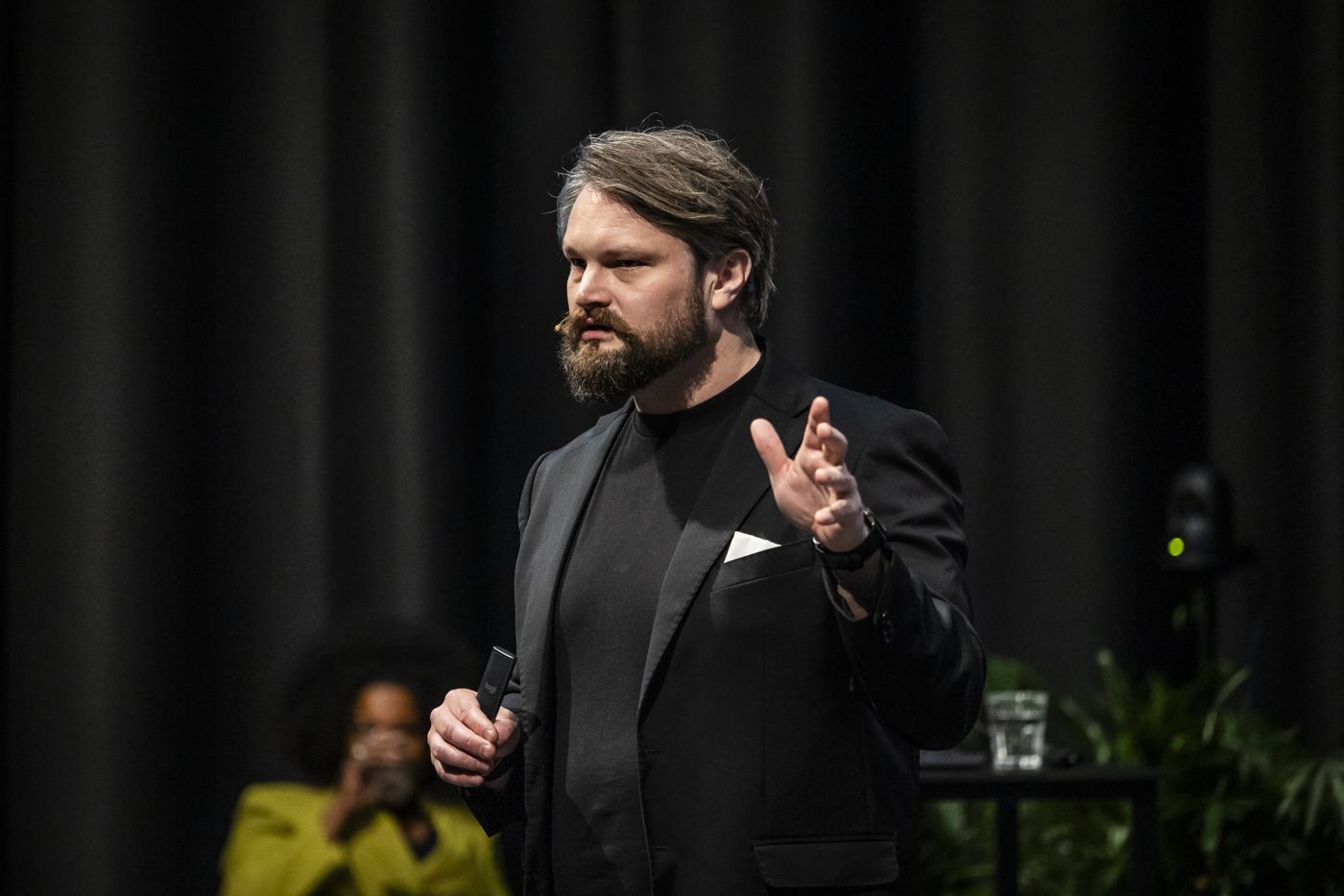 Aragorn sprekend op het podium, in het zwart